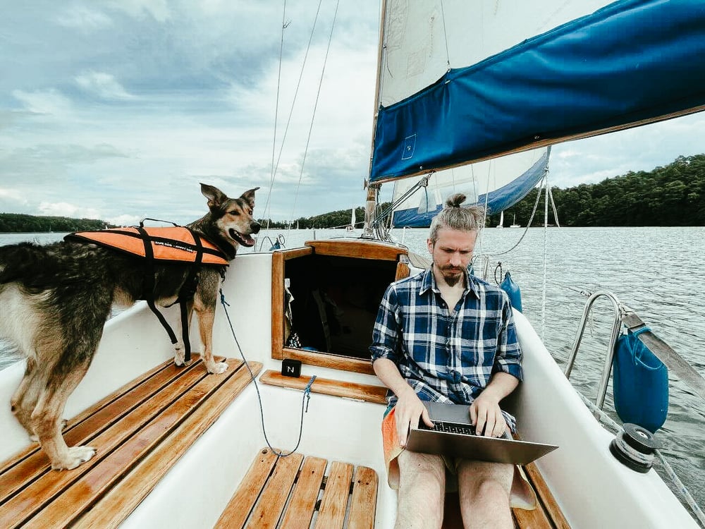 man working on a boat with his dog