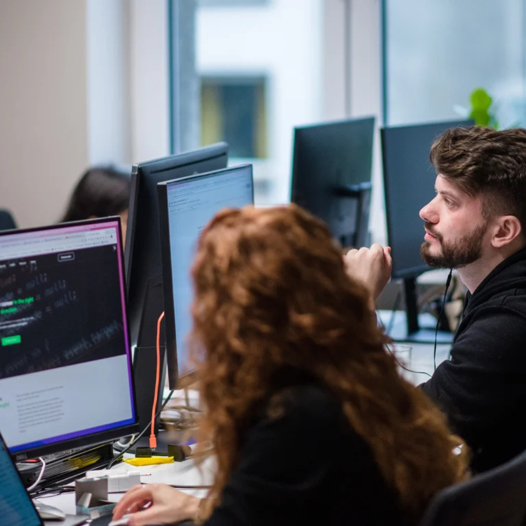 A woman and man - seen from the back - looking at computer screens