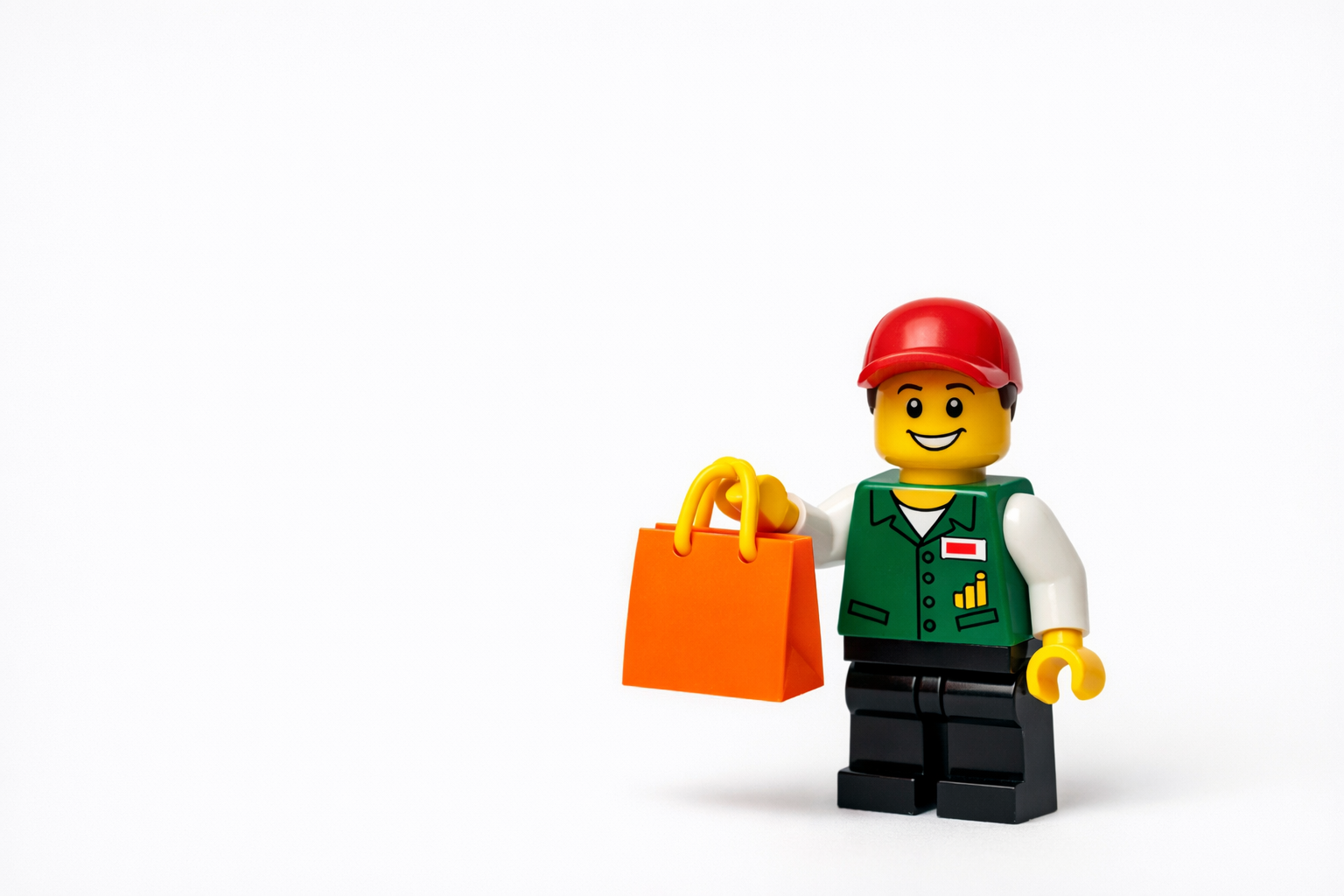 please give me a photo of lego figure who would be a shopping assistant handing a bag on a plain background make him smile and seems nice place him a-2