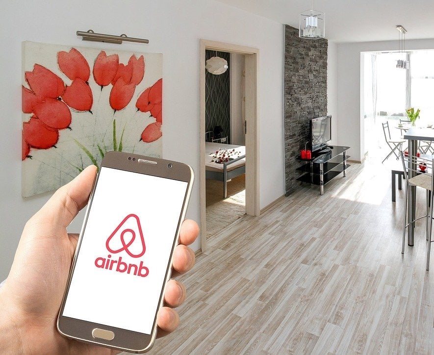 Man holding a mobile phone with airbnb app