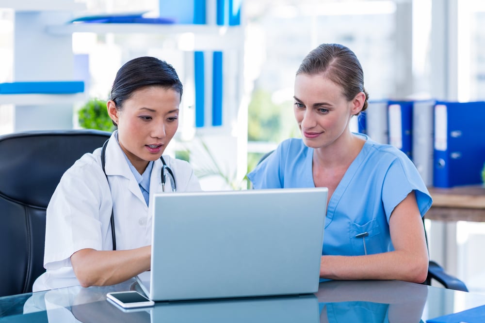Doctor and nurse looking at laptop in medical office-2
