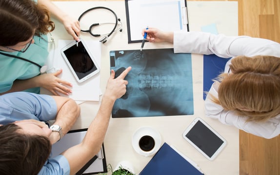 Doctors sitting around the table and interpreting x-ray image-1