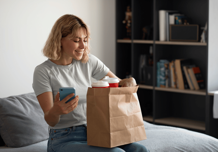 Woman opening up a paper bag with groceries.