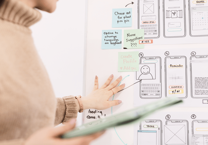 Designer next to a board with wireframes.