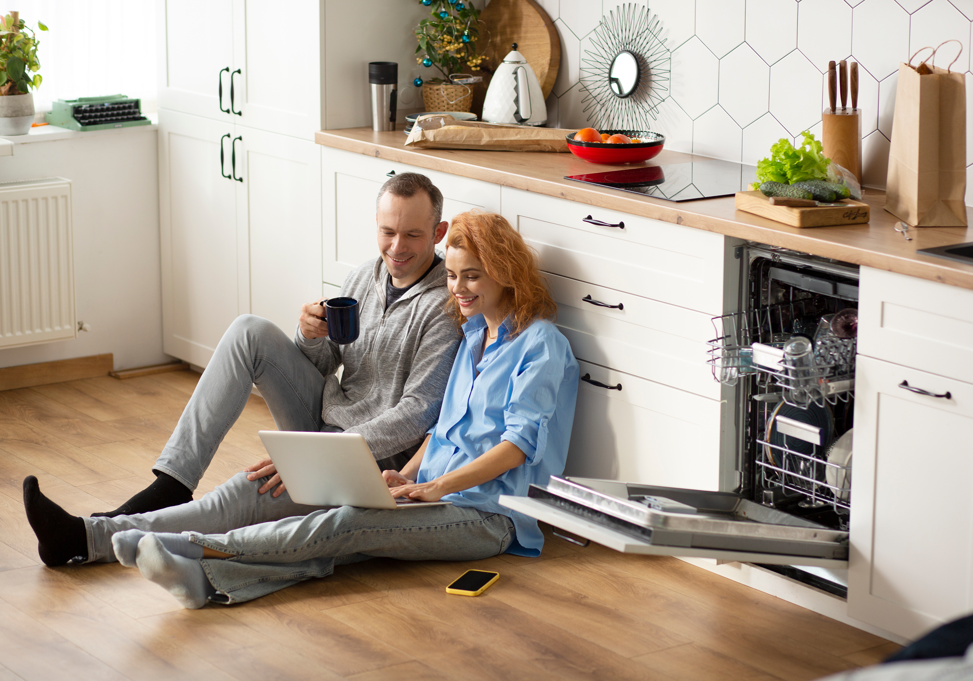 A couple sitting on the floor with a laptop.