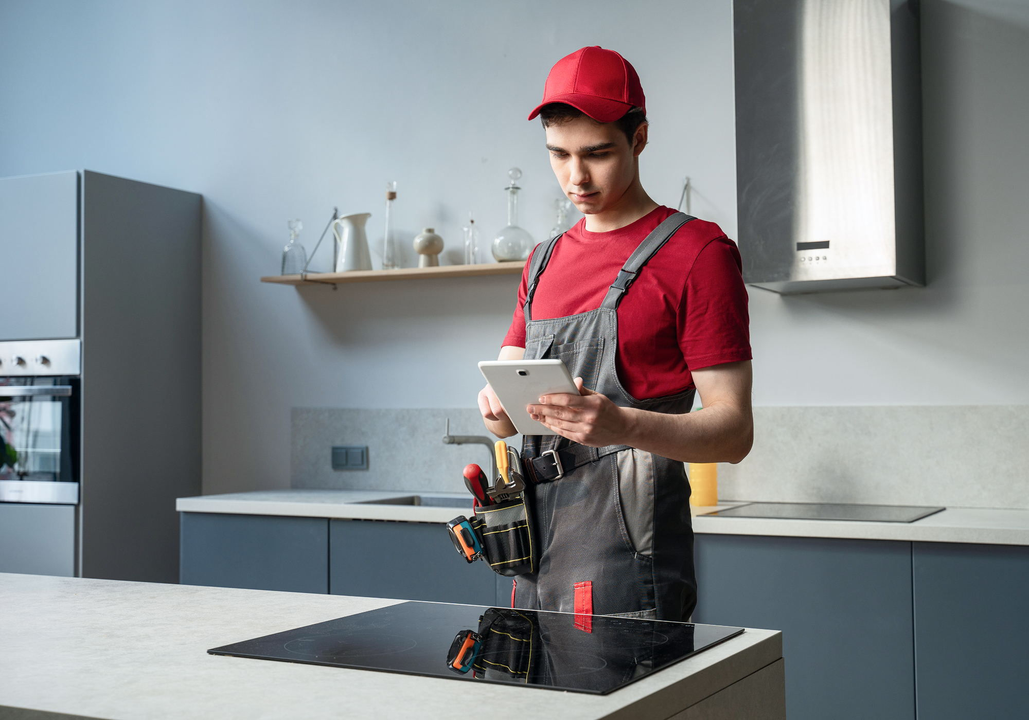 A repairman in a kitchen with a pad.