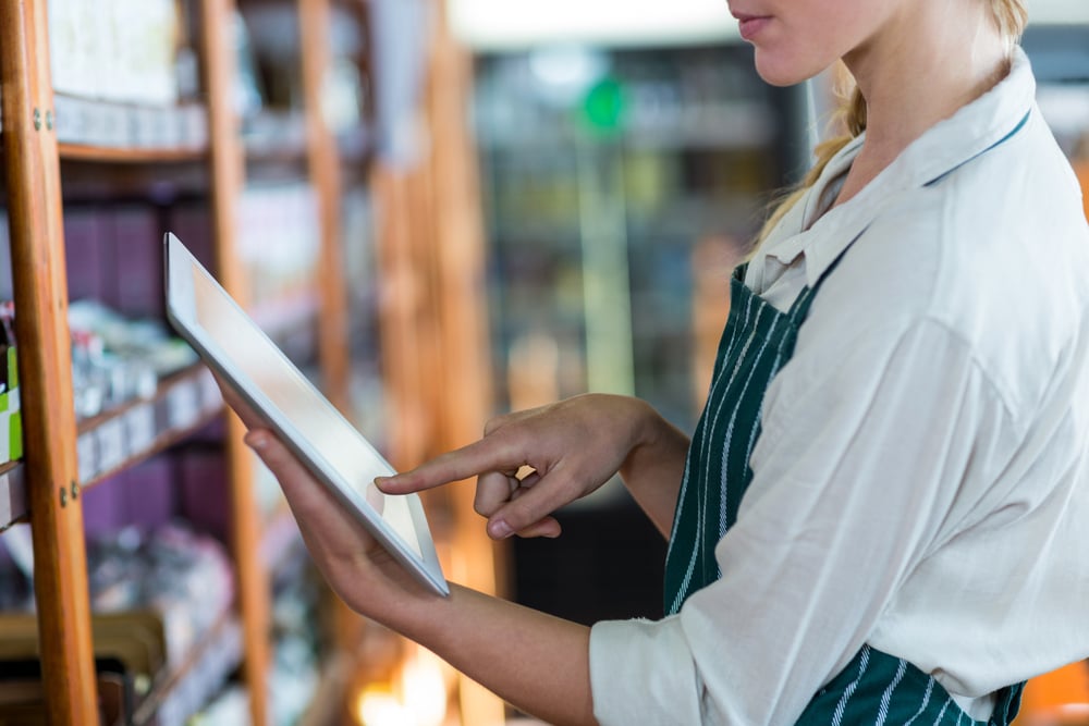 Mid-section of female staff using digital tablet in super market-1