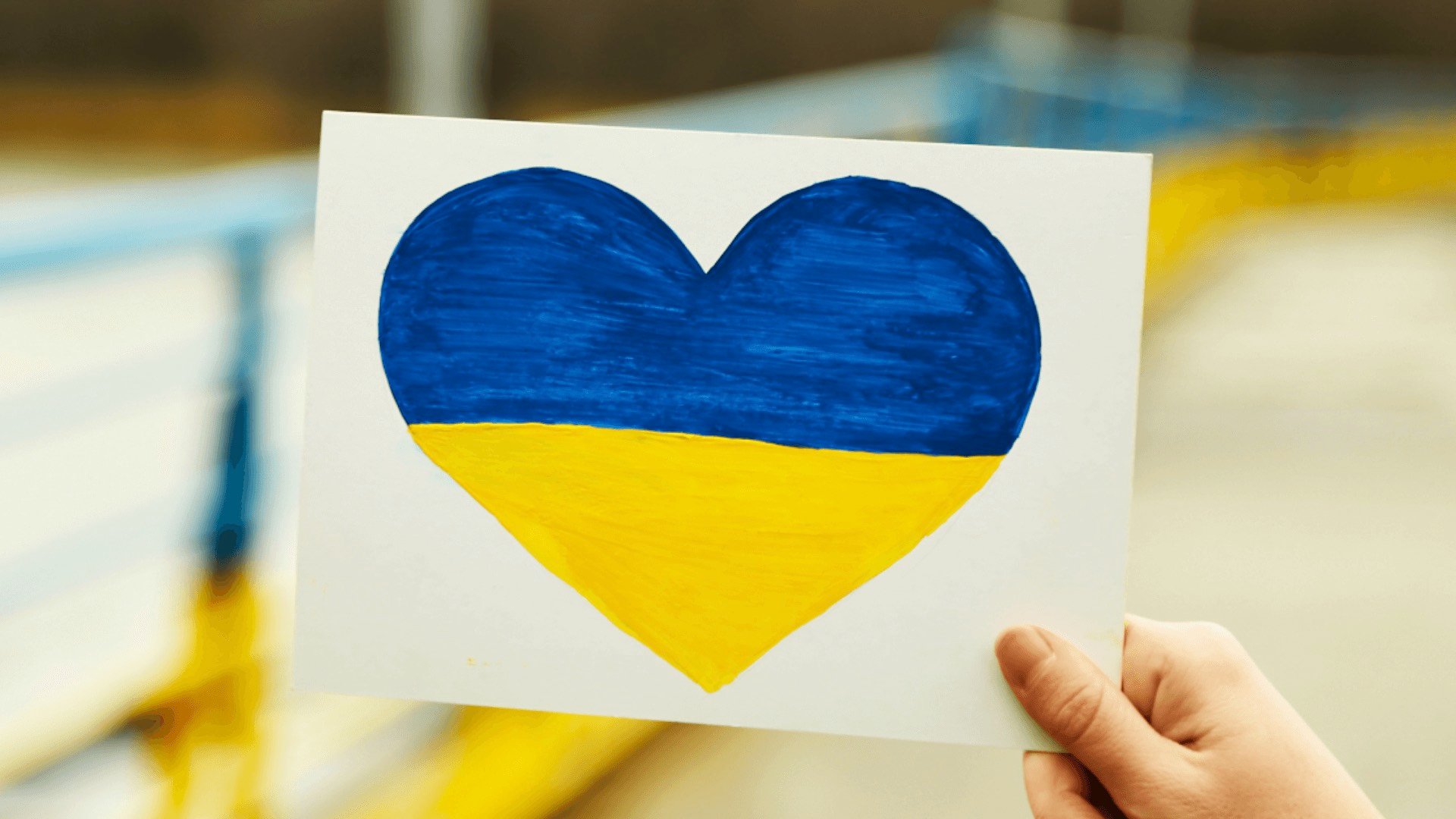 Person holding a card with an Ukrainian flag
