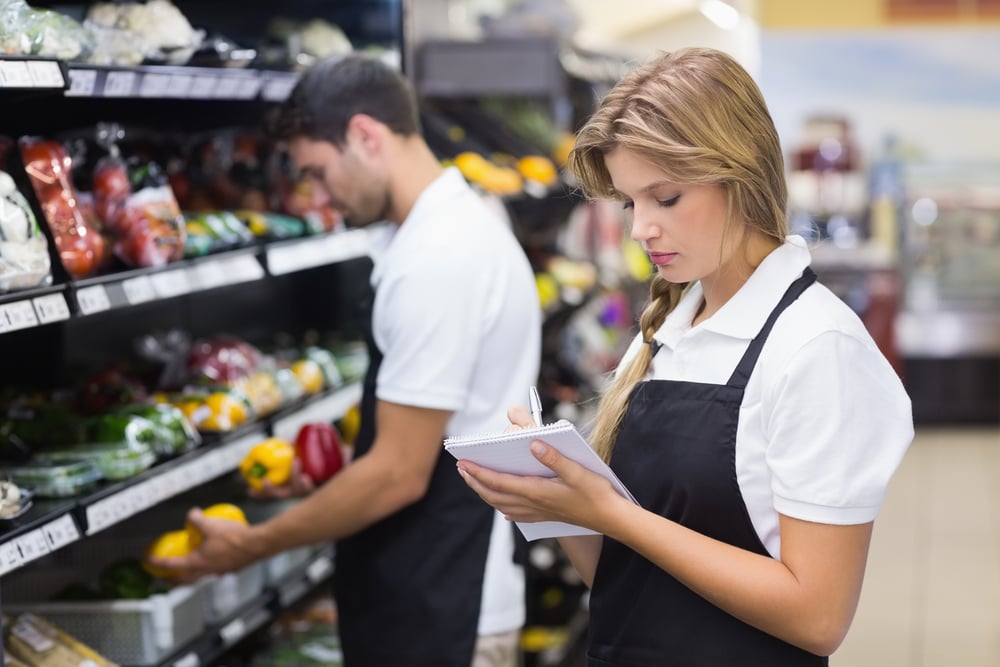 Serious staff woman wrting on notepad at supermarket-2