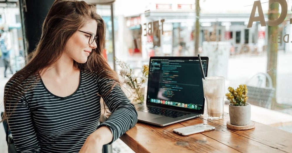 a woman looking at the code on the screen sitting in a restaurant