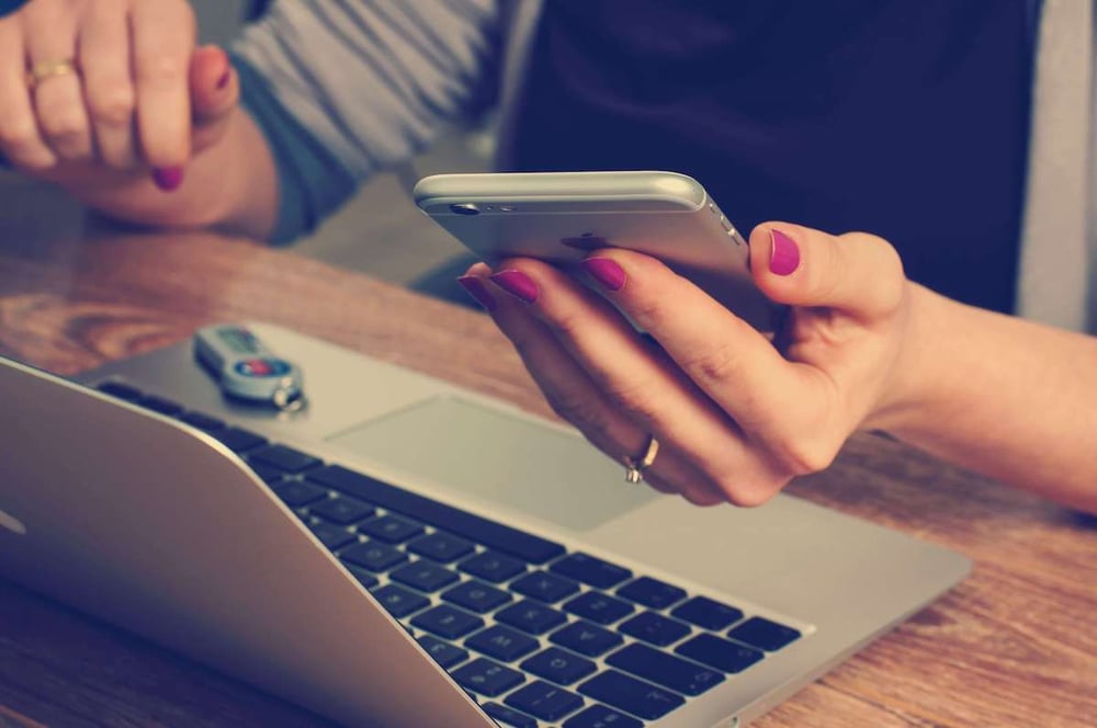 Woman holding a phone in front of the laptop