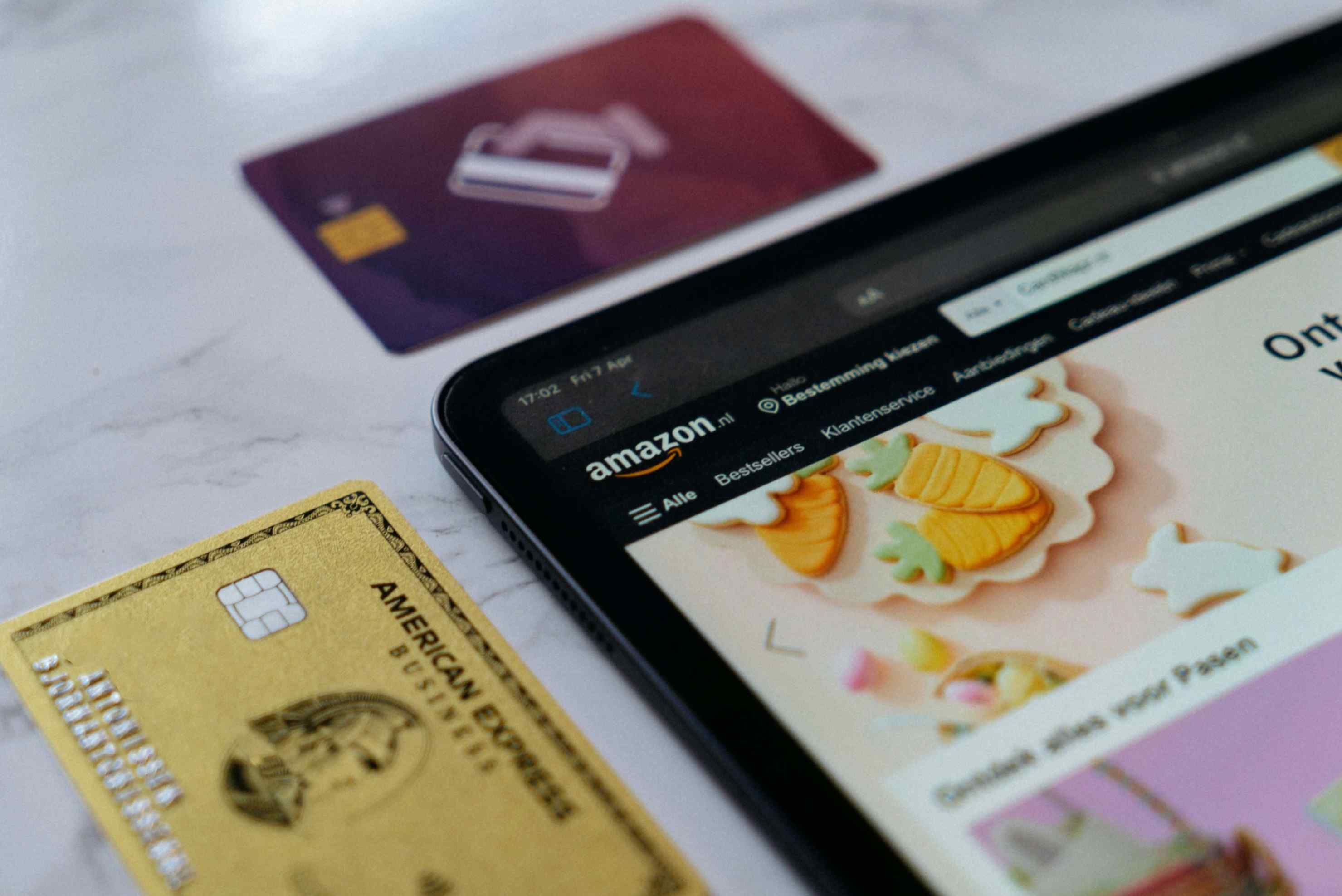 close-up of two credit cards and part of a tablet displaying Amazon website