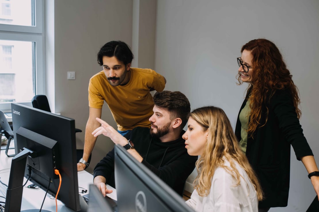 group of software developers pointing and looking at a screen