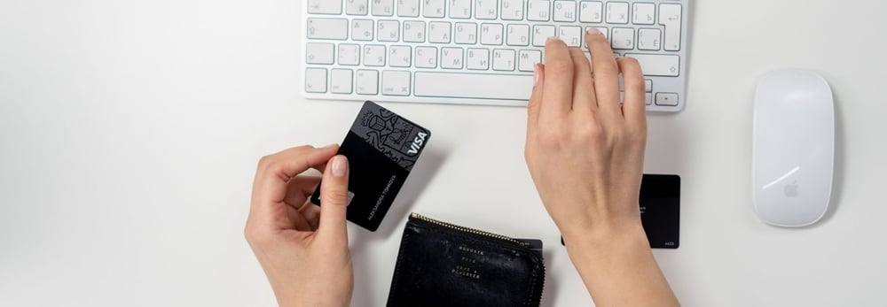 woman typing on a keyboard and holding a credit card