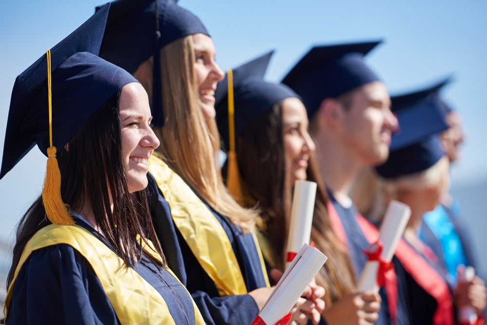 young graduates students group standing in front of university building on graduation day